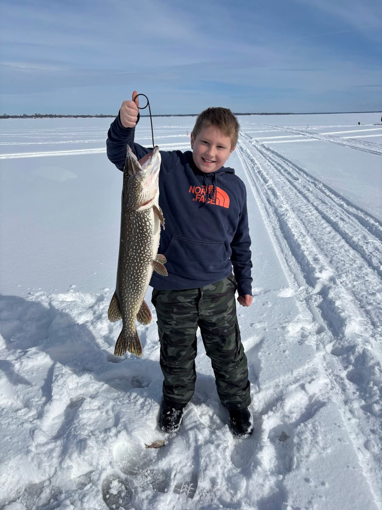 Gabe holding up a northern pike caught while ice fishing
